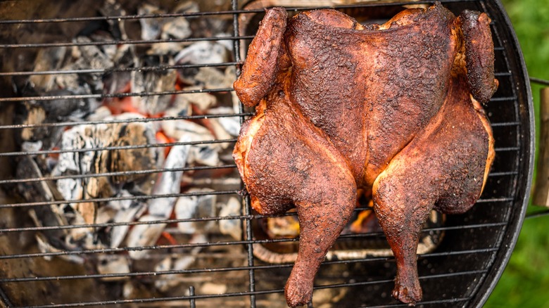 Whole spatchcock chicken cooking on the grill