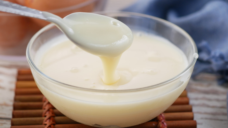 Taking a spoon of condensed milk from a clear bowl