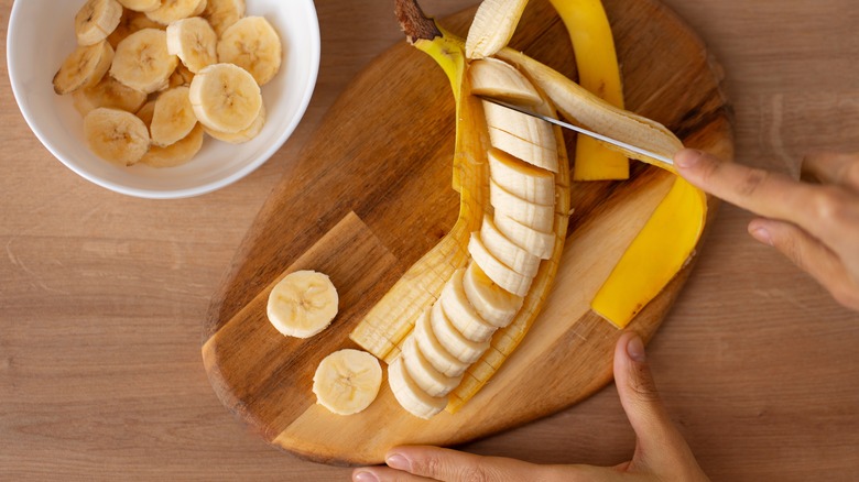 banana sliced in peel on wooden board