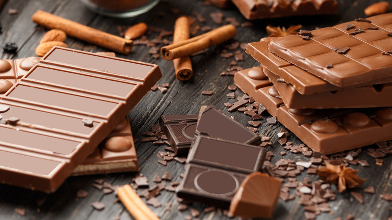 chocolate bars on wooden surface with chocolate pieces and shavings