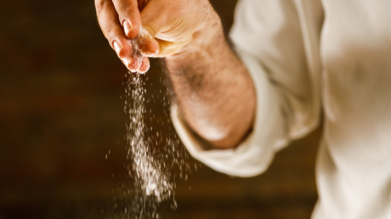 man sprinkling pinch of salt