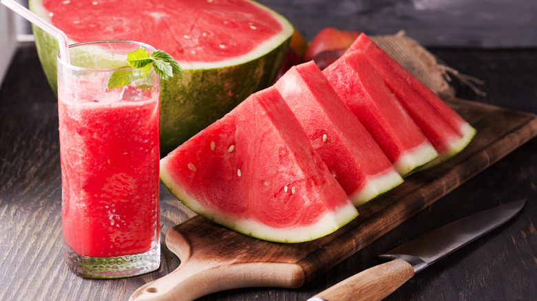 Sliced watermelon and watermelon drink on cutting board