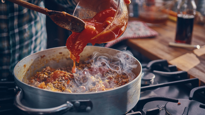 Person adding tomatoes to a pot