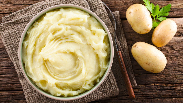 mashed potatoes in bowl with potatoes and herbs