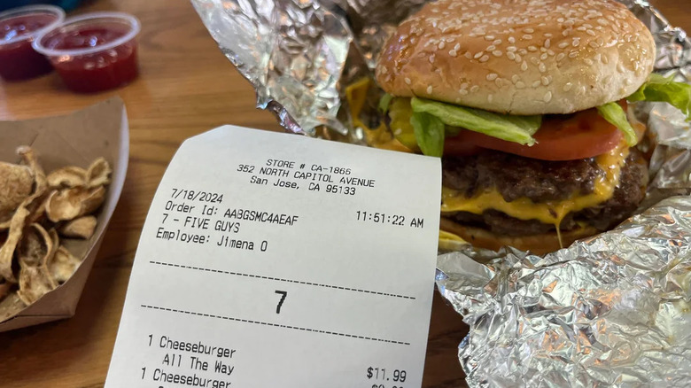 A close-up of a Five Guys burger taken "all the way" with a receipt.