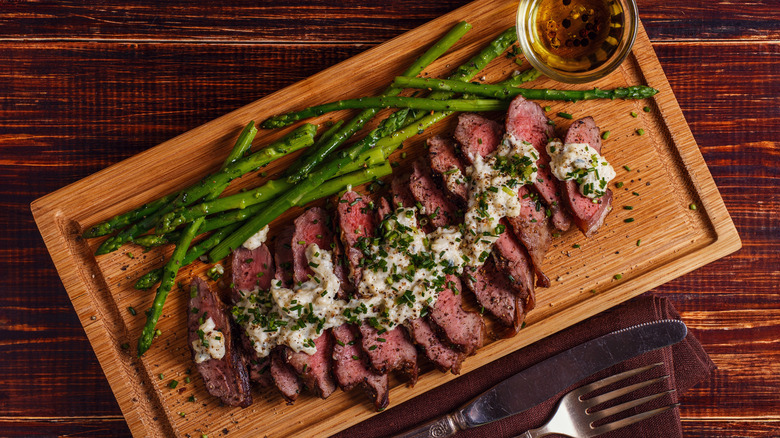 Slices of steak with blue cheese sauce and asparagus.