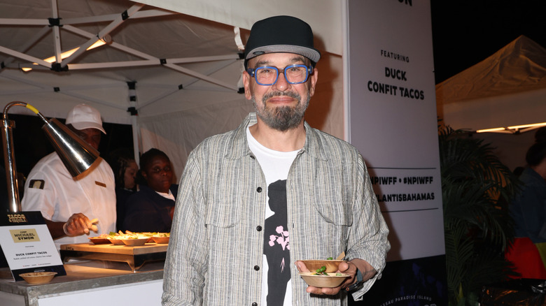 Chef Michael Symon holds small bowls while posing at a cooking demonstration