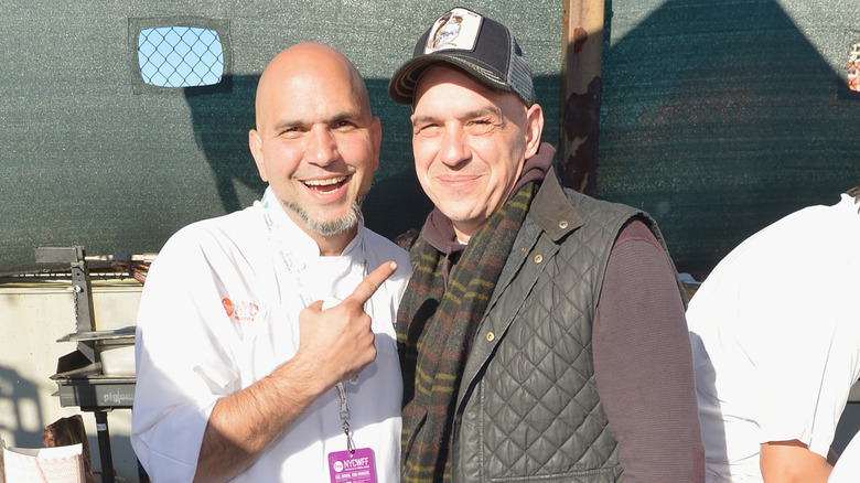 Chef Michael Psilakis points at Chef Michael Symon during an outdoor cooking exhibition