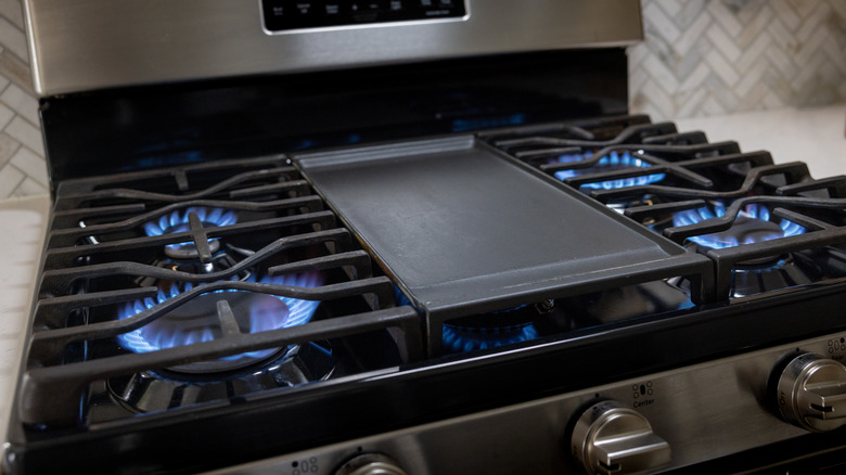 Close up of a stainless steel and black gas stove top with all burners on