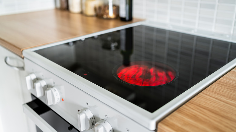 Close up of an induction stove that's on with wood countertops on both sides