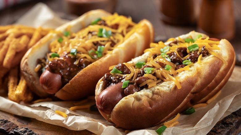 Two chili cheese dogs on a tray with fries.
