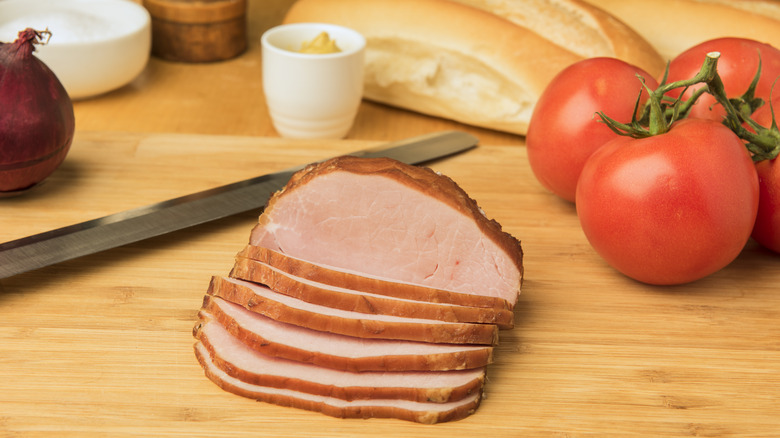 Canadian bacon on a wooden board with tomatoes