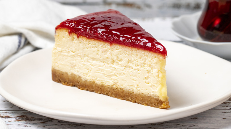 slice of cheesecake with strawberry jam on white plate