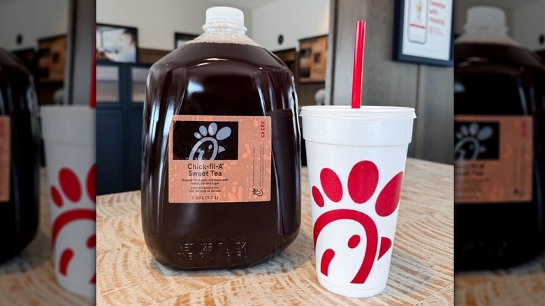 Gallon of Chick-fil-A sweet tea next to a branded cup with a red straw