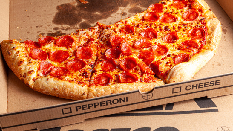 A half-eaten Costco pizza with approximately 6 slices left sits in a cardboard box