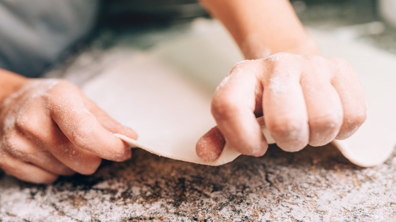 Hands stretching out pizza dough