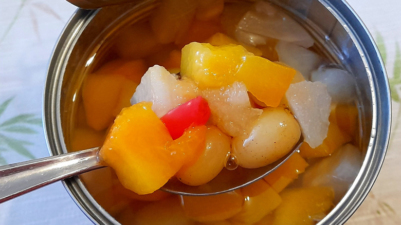 A can of fruit cocktail with a spoon on top