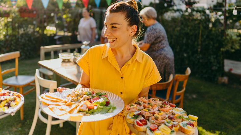 Woman carrying plates of food at outdoor party