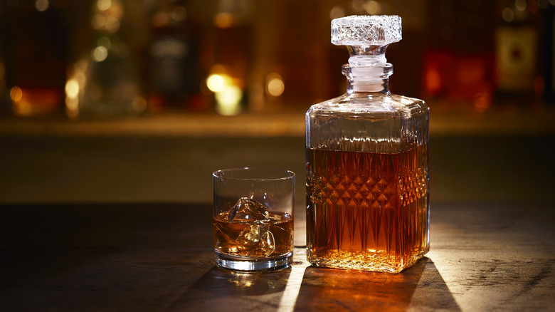 Whiskey decanter and glass of whiskey on the rocks at the bar