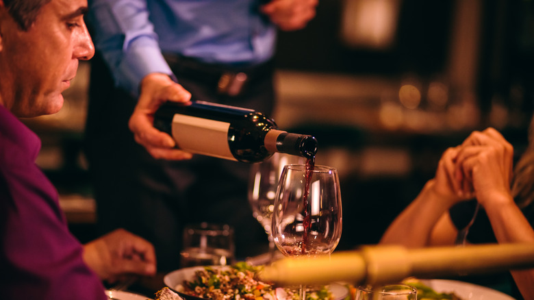server pouring wine to taste