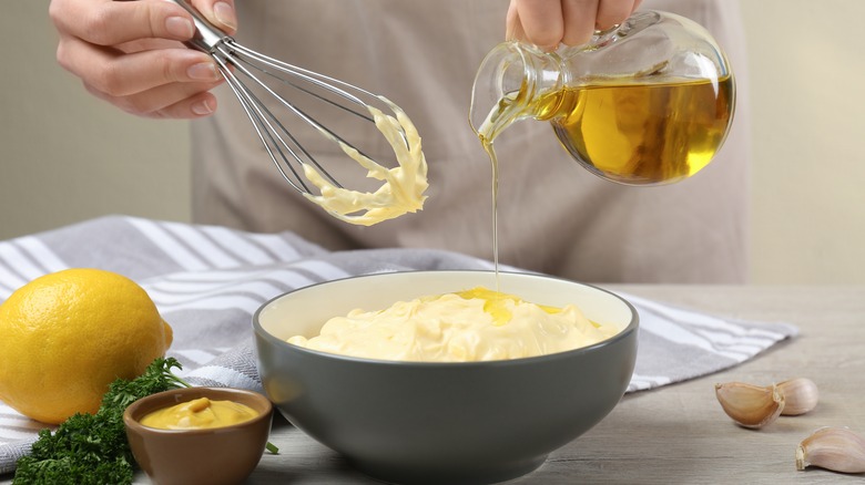 Person pouring oil into mayonnaise