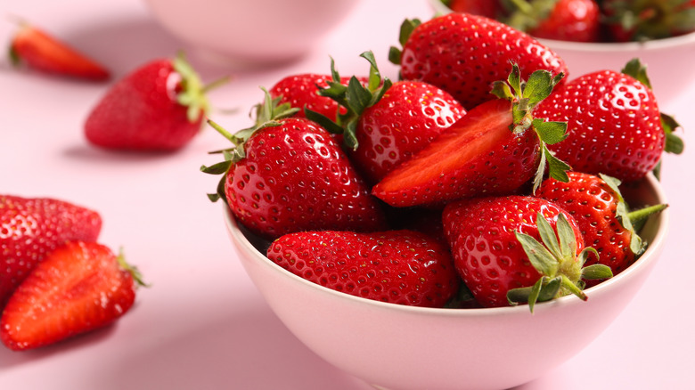 Strawberries with leaves in a pink bowl