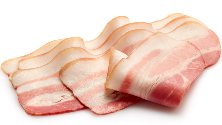 slices of raw bacon on white background