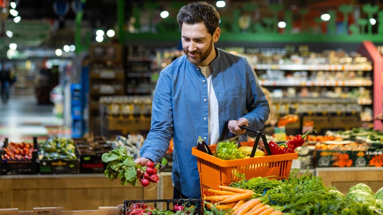 A shopper selects radishes at a grocery store