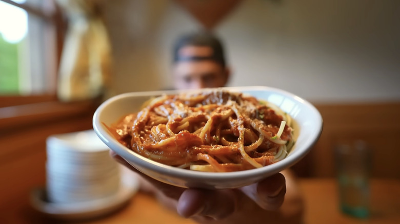 A diner holds a pasta dish at Olive Garden.