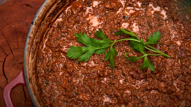 A ragù alla bolognese with parsley garnish in steel pot