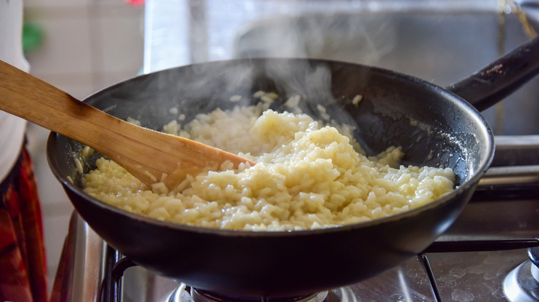 Spoon stirring risotto in a pan with a wooden spoon