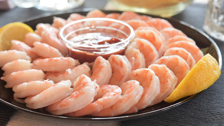 platter of shrimp cocktail with sauce and lemon
