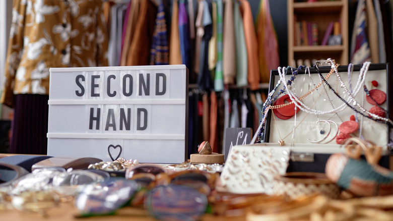 A thrift store with a "second hand" sign on a table of mixed used goods