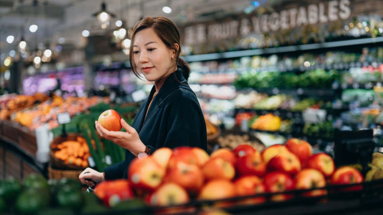 A shopper browses apples in supermarket