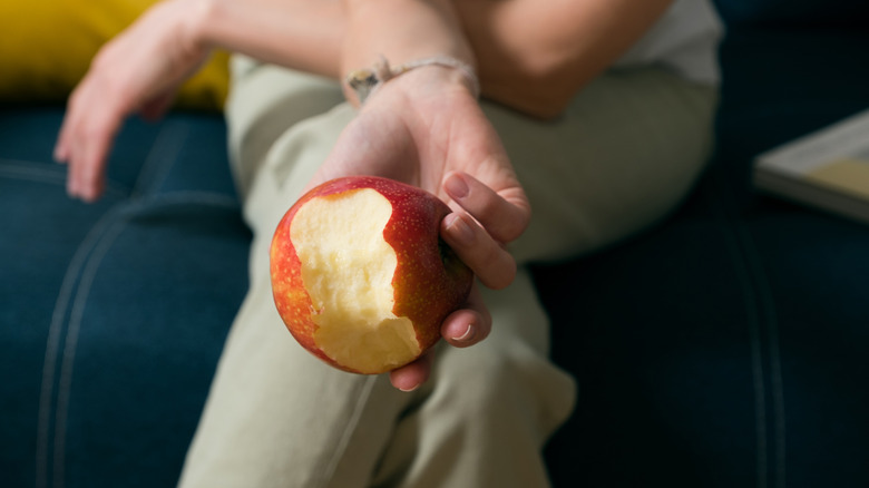 A person sitting cross legged as they eat an apple