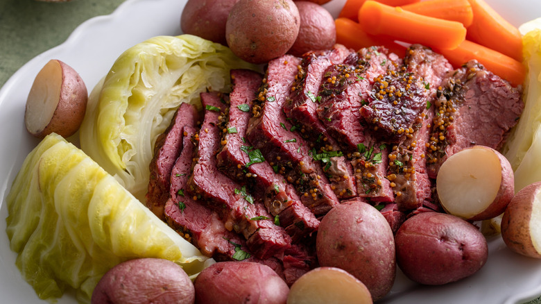 Traditional St. Patrick's Day corned beef, cabbage, potatoes, and carrots meal on a white plate.