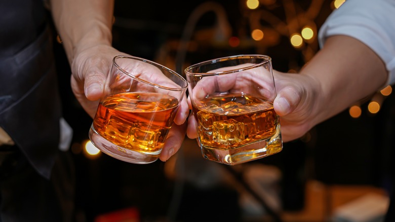 hands holding glasses of whiskey together