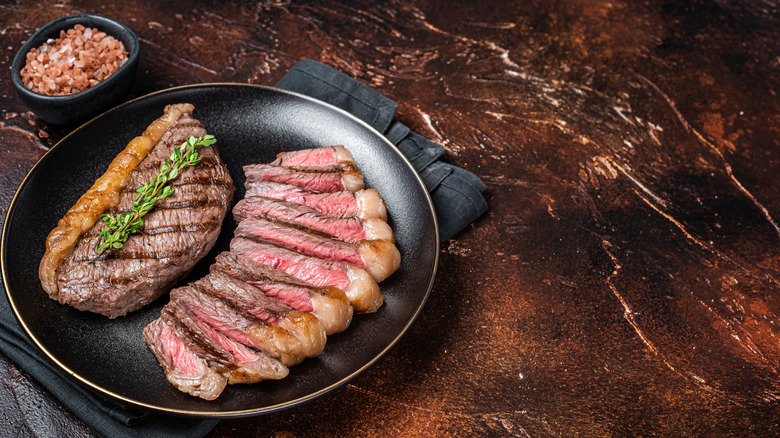 Grilled sirloin steak on a plate next to a bowl of salt