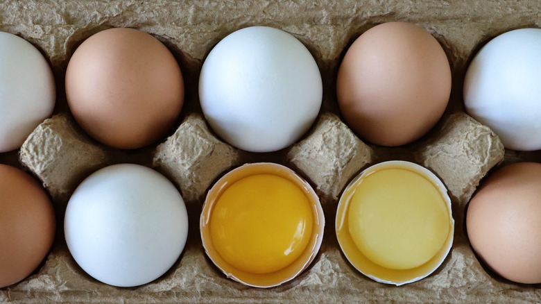 carton of white and brown eggs and yolks