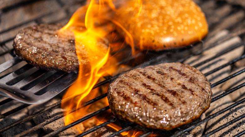 Burgers patties and hamburger bun on a grill with fire