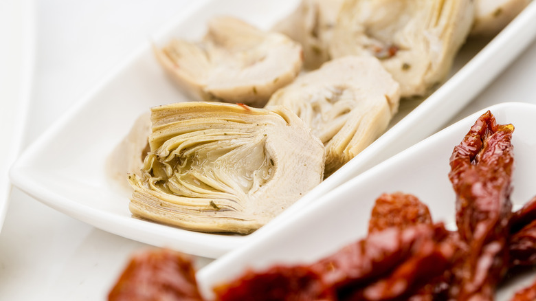 Artichoke hearts and sundried tomatoes sit on platters
