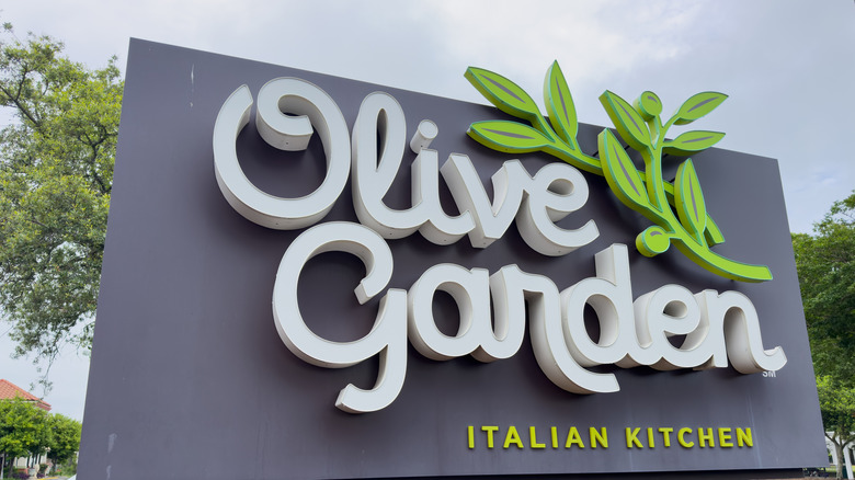 An Olive Garden Italian Kitchen sign under a blue sky