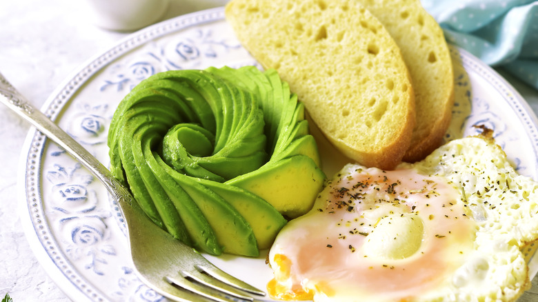 Avocado rose near a slice of toast and fried egg