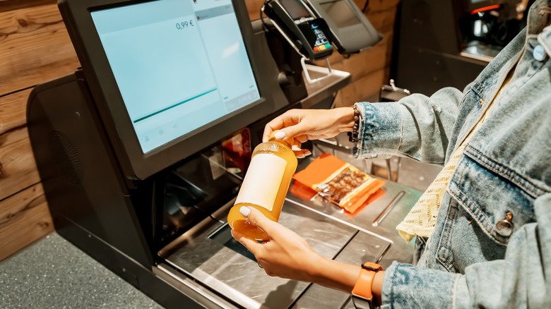 person scanning drink at self checkout