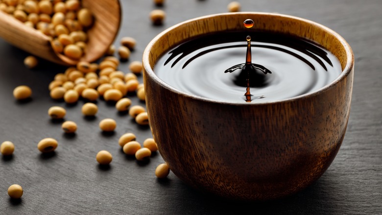 Bowl of soy sauce with dried soybeans on table