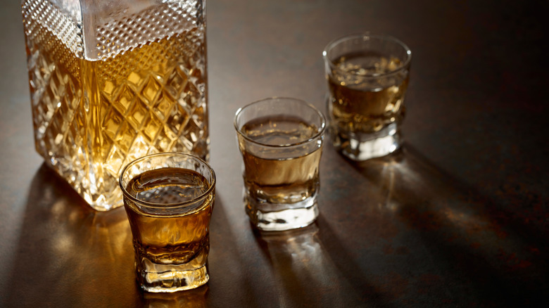 A whiskey decanter and three small glasses.