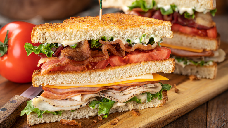 Layered club sandwich on toasted bread on a wooden board