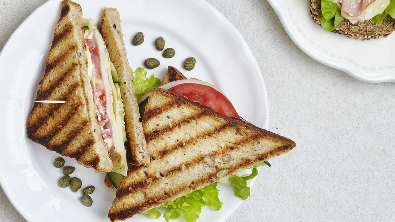 Sliced club sandwich held with a toothpick on a white plate