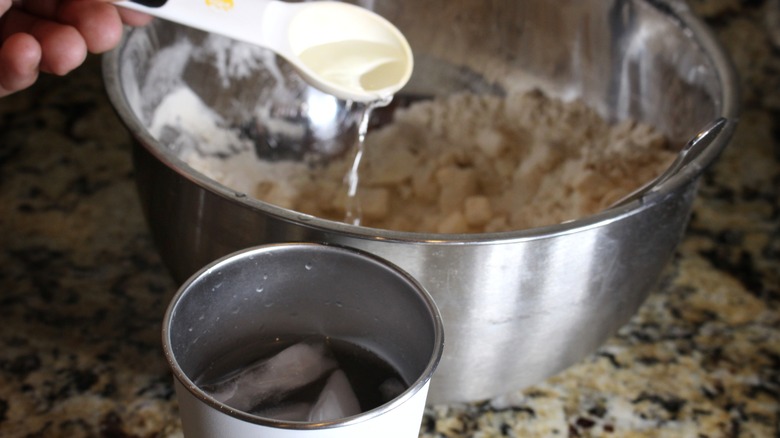 spoonful of ice water being added to bowl