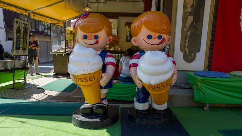 Nissei ice cream mascots statues stand in front of a shop.